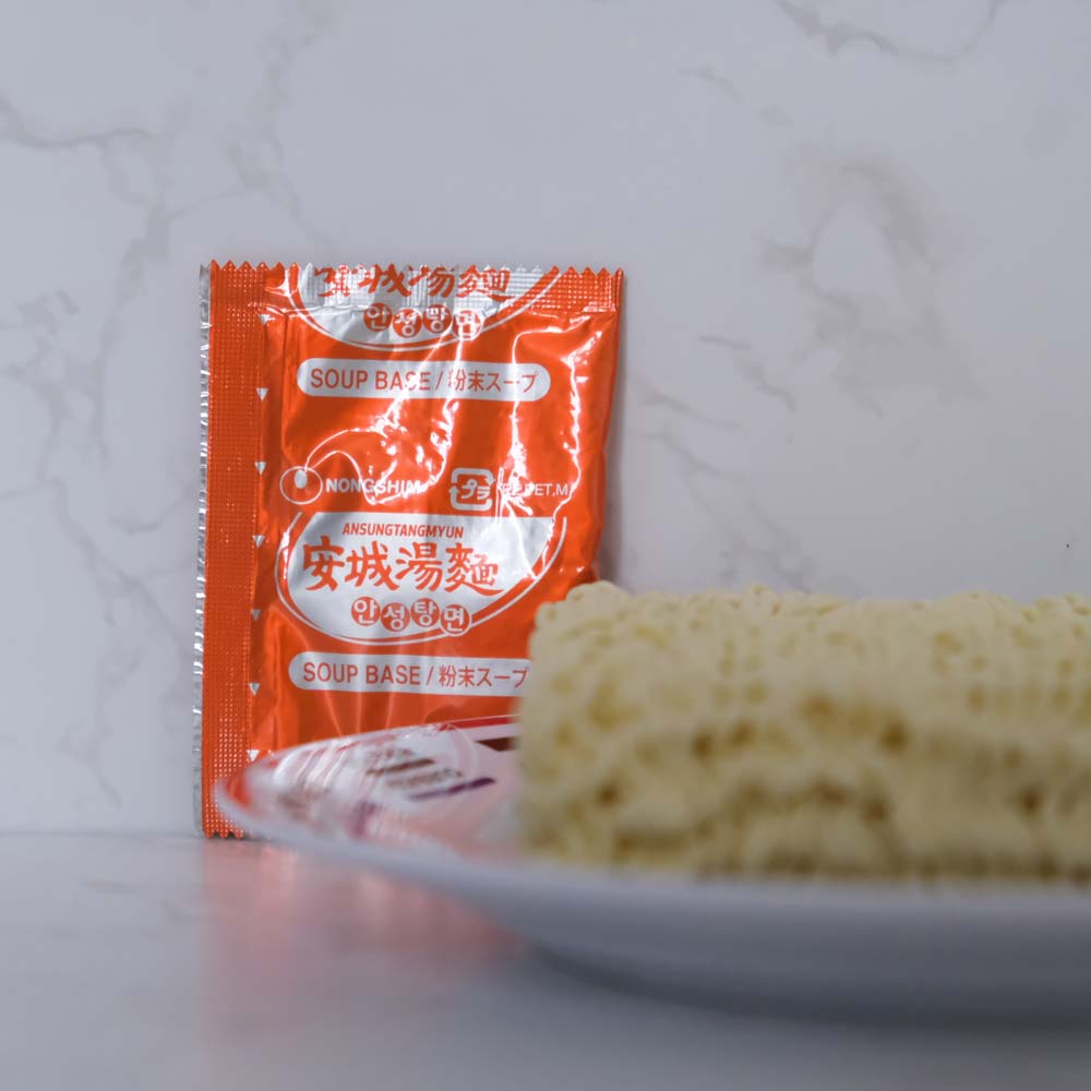 Cosa contiene la busta di Ansung Tangmyun di Nongshim con sfondo marmo e piatto di Scaffale Coreano