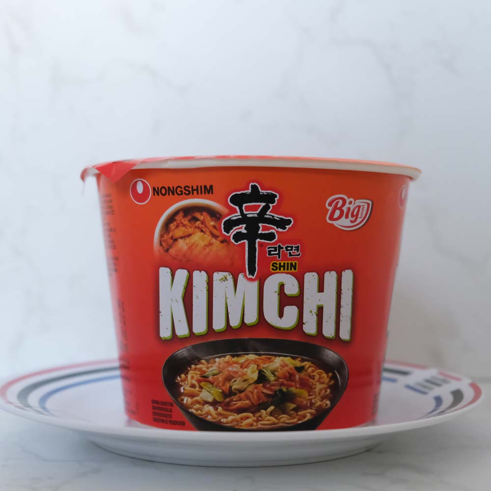 Bowl Noodle Kimchi di Nongshim con sfondo marmo e piatto di Scaffale Coreano