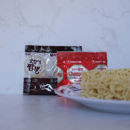 Cosa contiene la busta di Champong Ramyeon di Nongshim con sfondo marmo e piatto di Scaffale Coreano