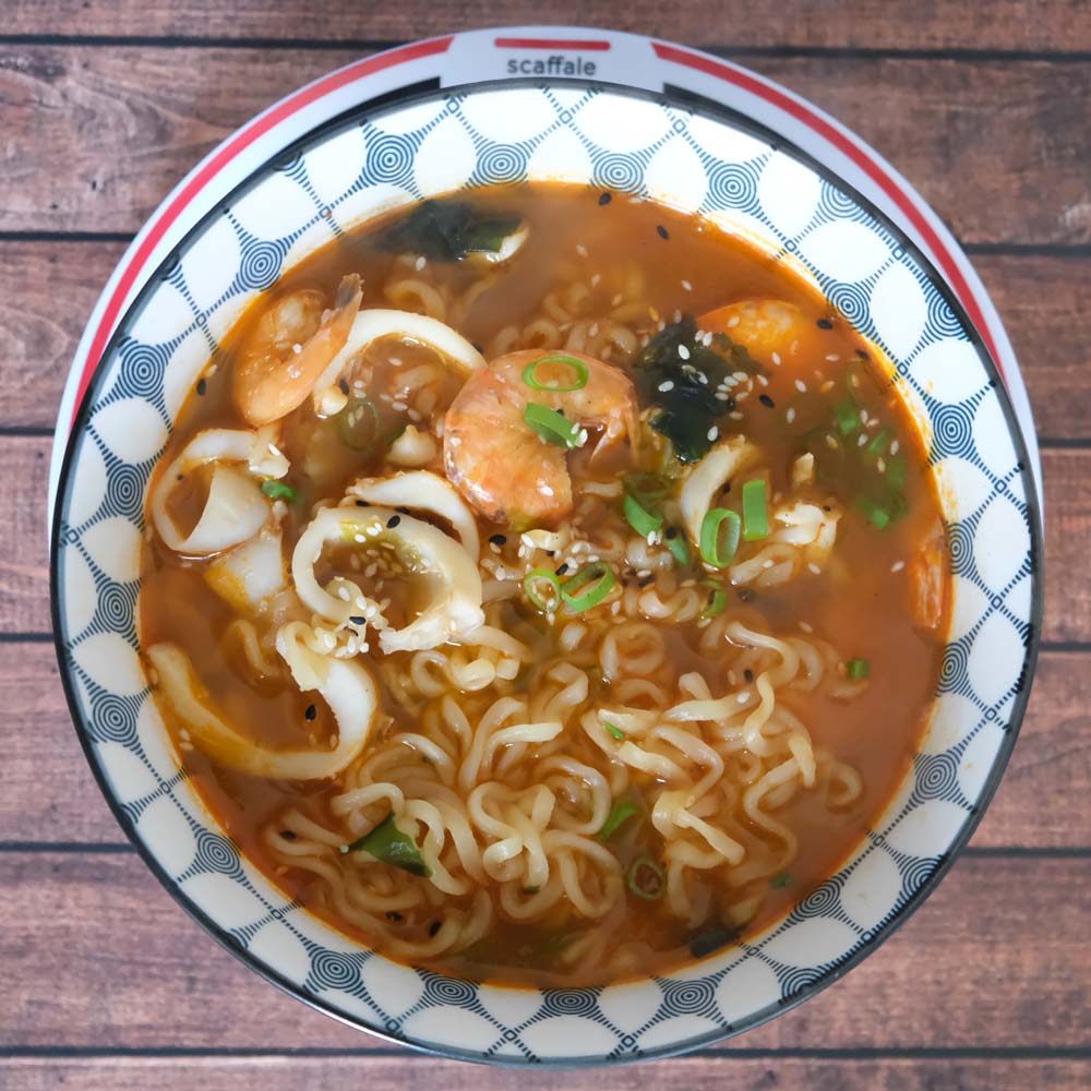 Piatto fumante di Champong Ramyeon di Nongshim con sfondo blu e legno e piatto di Scaffale Coreano