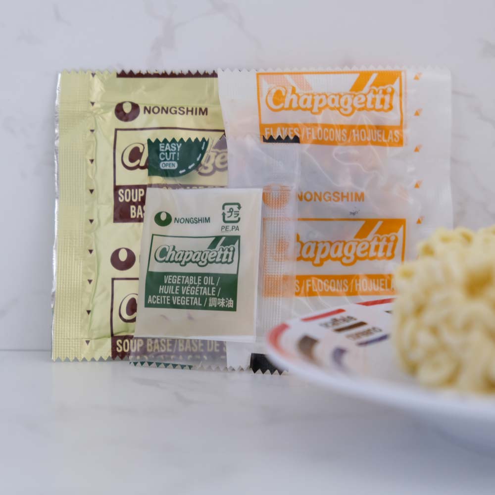 Cosa contiene la busta di Chapagetti Chajangmyun di Nongshim con sfondo marmo e piatto di Scaffale Coreano