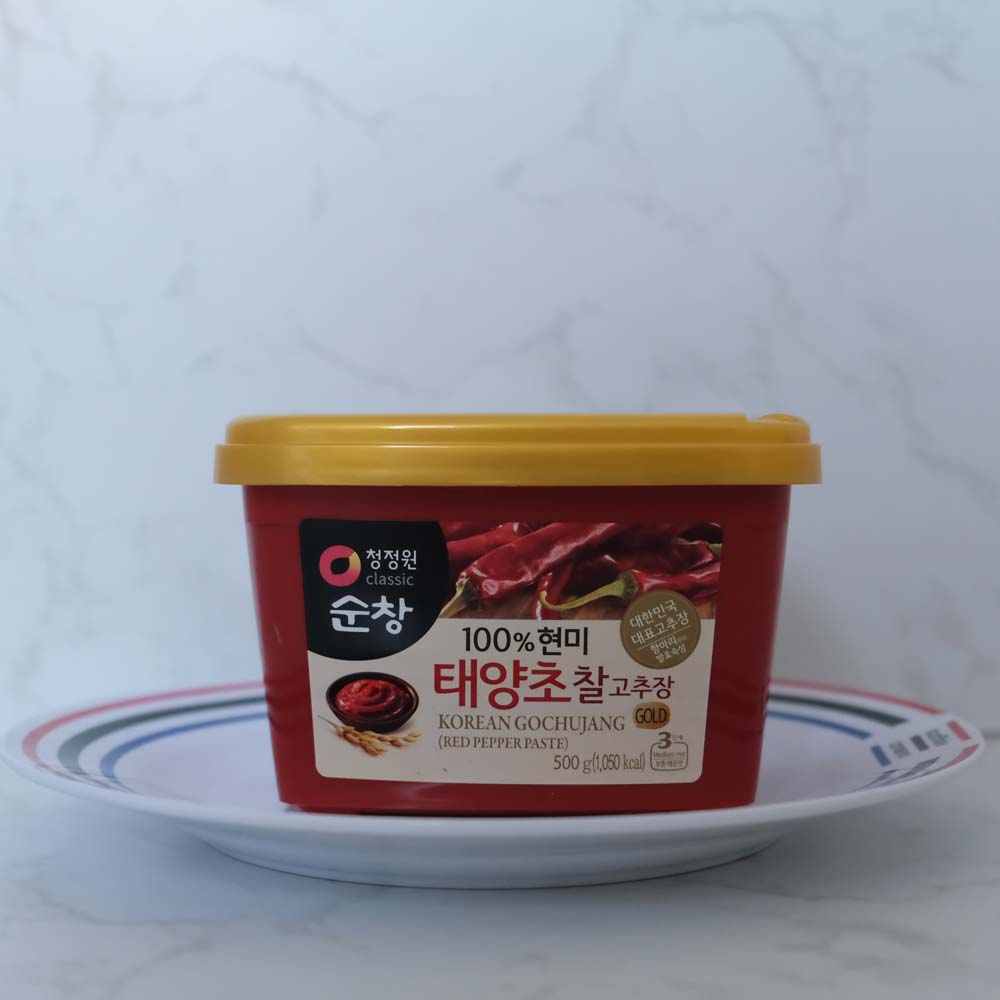 Gochujang pasta al peperoncino di Daesang Gochujang pasta al peperoncino di Sempio con sfondo marmo e piatto di Scaffale Coreano