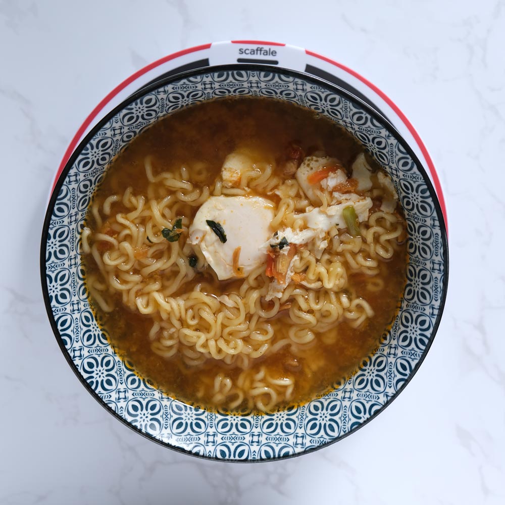 Piatto fumante di Kimchi Shin Ramyun di Nongshim con sfondo marmo e piatto di Scaffale Coreano dall'alto