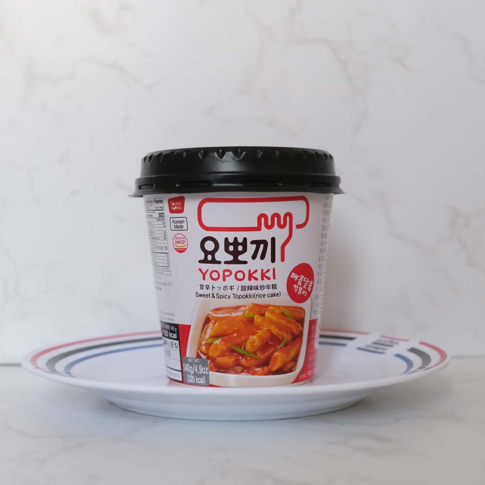 Tteokbokki agrodolci e piccanti cup di Youngpoong con sfondo marmo e piatto di Scaffale Coreano