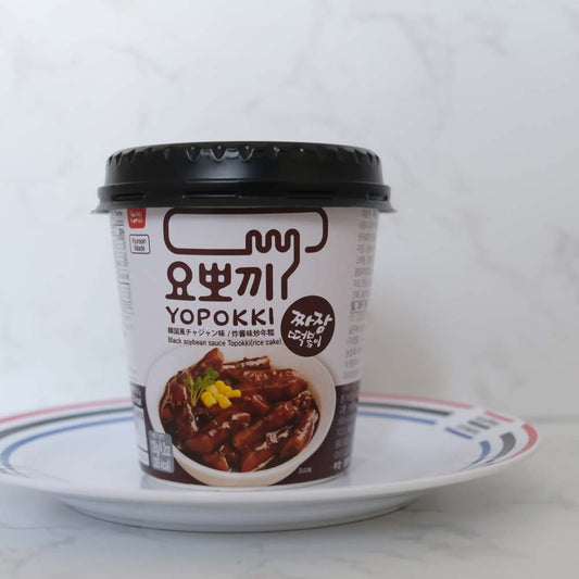 Tteokbokki jjajang cup di Youngpoong con sfondo marmo e piatto di Scaffale Coreano