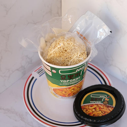 Yopokki Rapokki Curry Cup con sfondo marmo e piatto di Scaffale Coreano