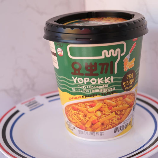 Yopokki Rapokki Curry Cup con sfondo marmo e piatto di Scaffale Coreano