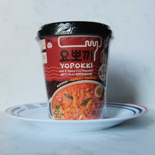 Rapokki Hot & Spicy Yopokki con sfondo marmo e piatto di Scaffale Coreano