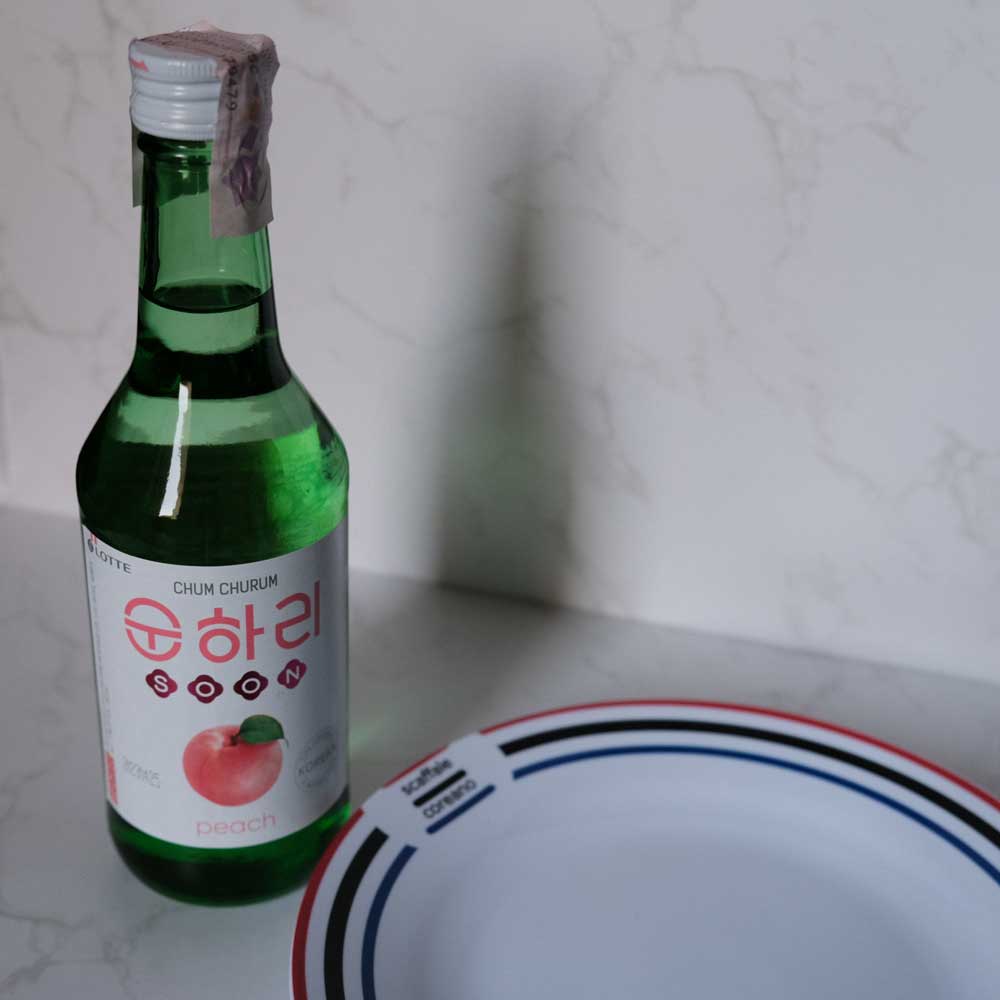 Bottiglia di Soju alla Pesca con sfondo marmo e piatto di Scaffale Coreano