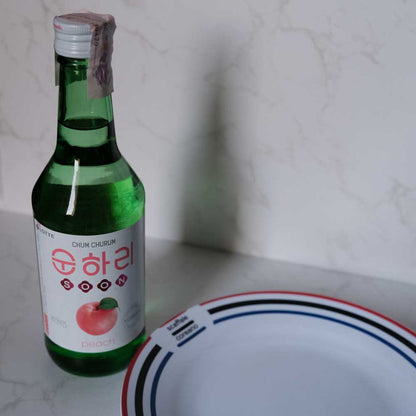 Bottiglia di Soju alla Pesca con sfondo marmo e piatto di Scaffale Coreano