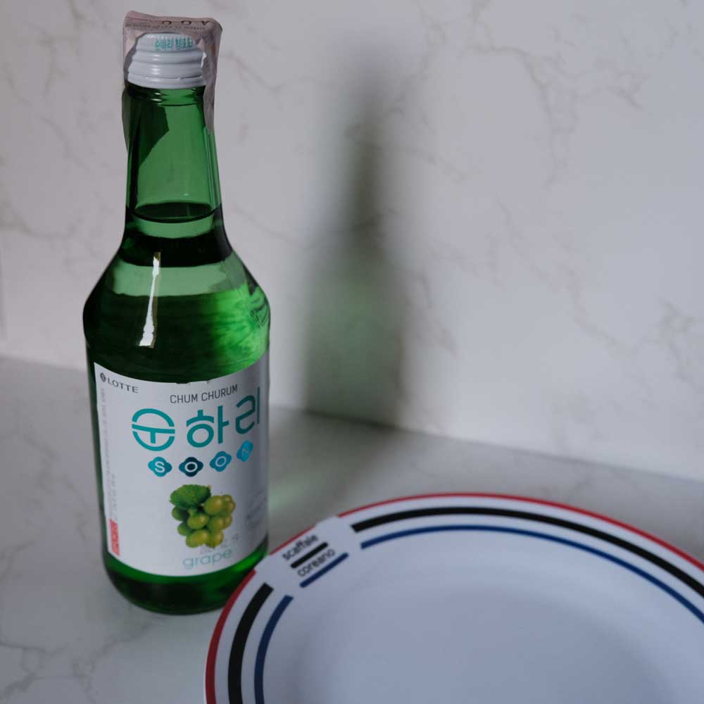 Bottiglia di Soju all' Uva con sfondo marmo e piatto di Scaffale Coreano