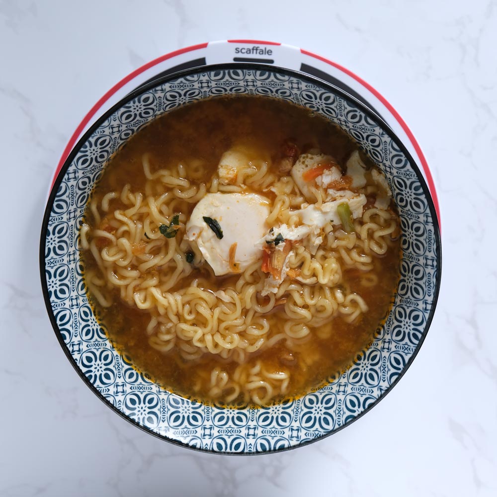 Piatto fumante di Kimchi Shin Ramyun di Nongshim con sfondo marmo e piatto di Scaffale Coreano