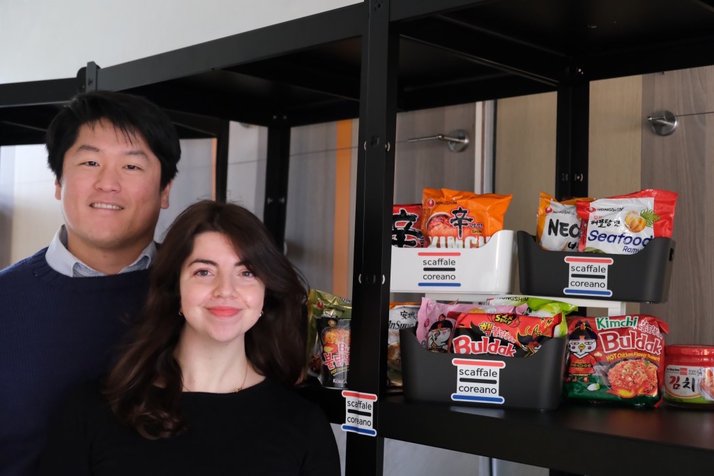 Immagine di Francesca e Kyeong-uk proprietari di Scaffale Coreano accanto a scaffali con Ramyun e Kimchi